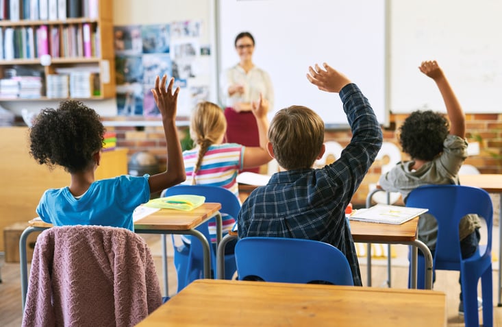 children raising their hands in a classroom