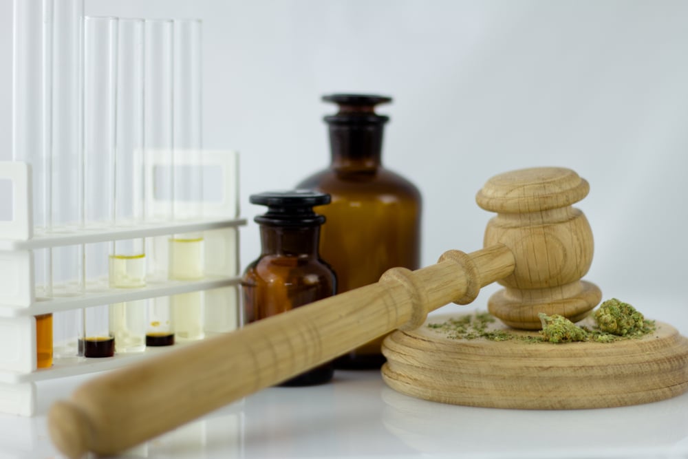 Cannabis oil with apothecary jar and wooden judge hammer with sound block on the white mirror