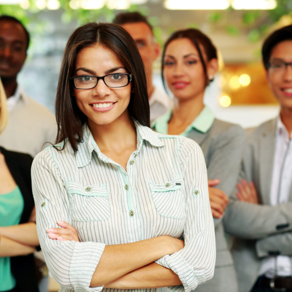 smiling-businesswoman-with-arms-folded-standing-in-front-her-colleagues-scaled-1152x1152-Jul-27-2023-11-03-51-5735-AM